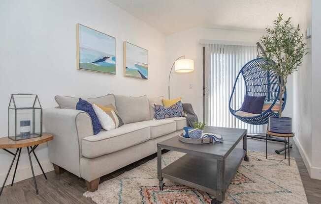 A living room with a white couch, a coffee table, and a hanging chair.