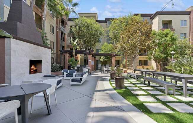 A patio with a fireplace and chairs. at The Kitt at Warner Center Apartments, Woodland Hills, CA, 91303