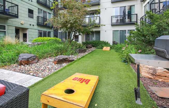 an apartment yard with a yellow bench and a grill