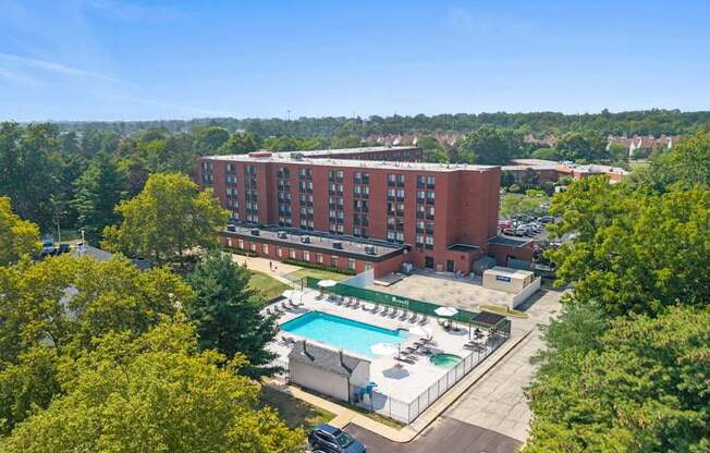 A large red brick building with a pool in front.