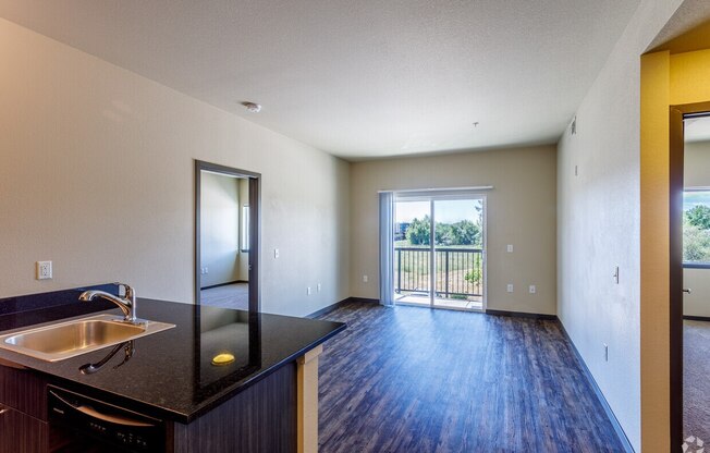 a kitchen and living room with a door to a balcony