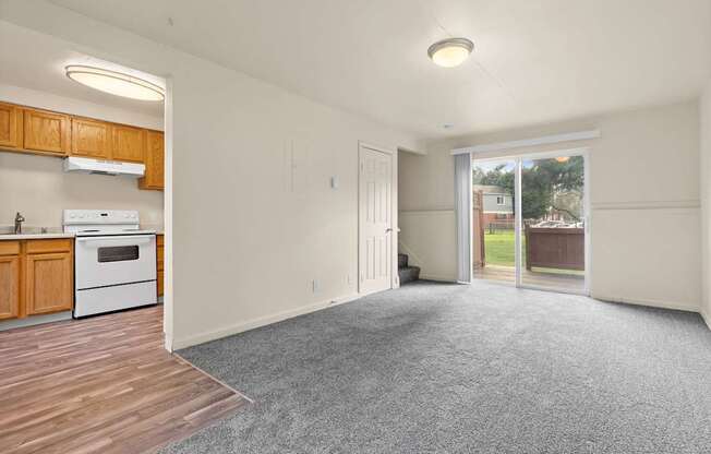 A large empty room with a kitchen area to the left.