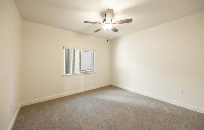 A room with a ceiling fan and a window.