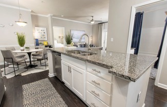 an open kitchen with granite counter tops and a dining room with a table at Ansley at Town Center in Evans GA