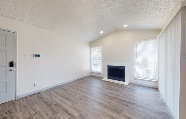 an empty living room with a fireplace and white walls