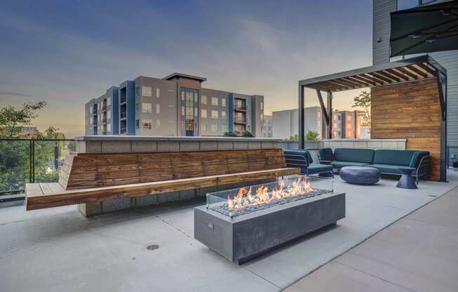 a lounge area with a fire pit and benches on a patio