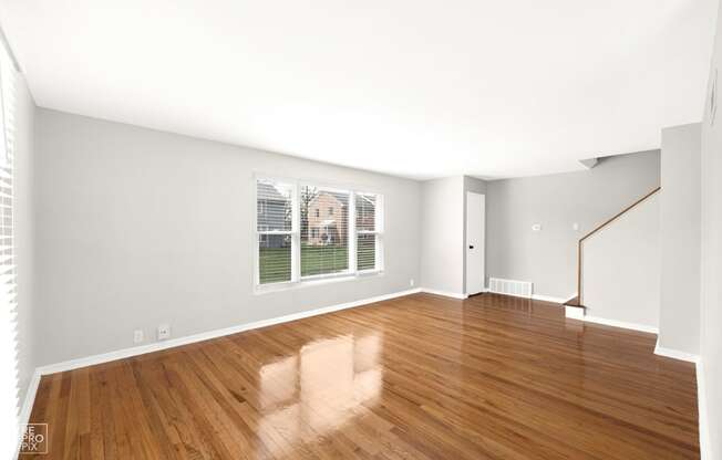 a bedroom with hardwood floors and a large window