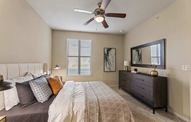 A bedroom with a bed, dresser, and a ceiling fan.