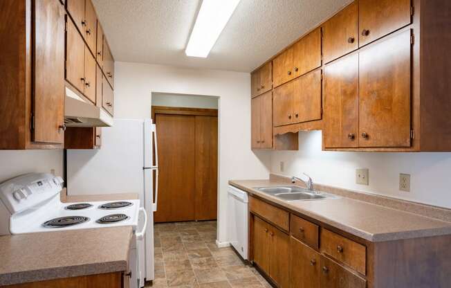 a kitchen with a stove and sink and a refrigerator. Fargo, ND Betty Ann Apartments