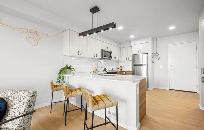 a kitchen with white cabinetry and a large white island with a white countertop and yellow at Ion Town Center, Shoreline Washington