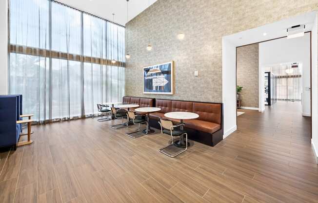 a seating area with tables and chairs in front of a wall of windows