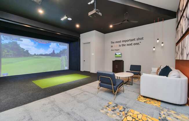 a living room with a large screen on the wall and a couch and chairs