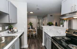 an open kitchen and dining room with white cabinets and marble counter tops