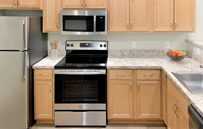 Corner style kitchen with wood cabinets and a stainless steel stove and microwave at 6 Wood Flats, Washington, 98503
