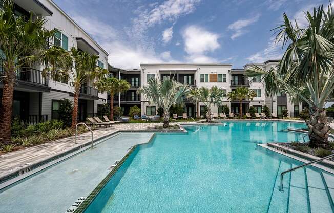 a large swimming pool with palm trees in front of apartment buildings