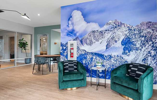 a room with two green chairs and a large mural of a snowy mountain on the wall