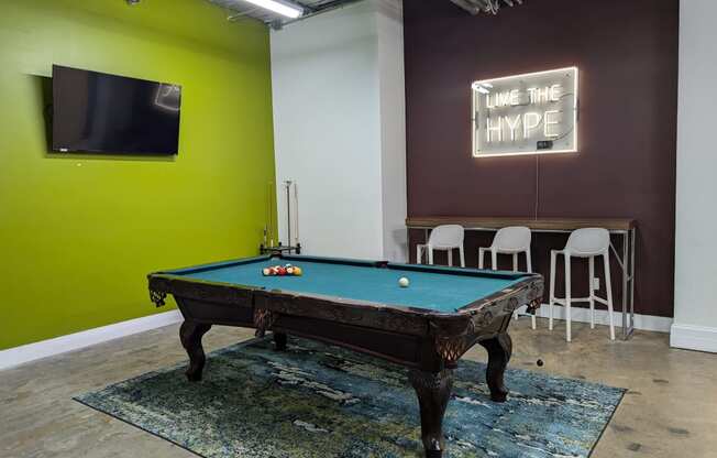 a pool table in a room with a tv and a green wall