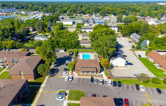 A bird's eye view of a residential area with a swimming pool and parked cars.