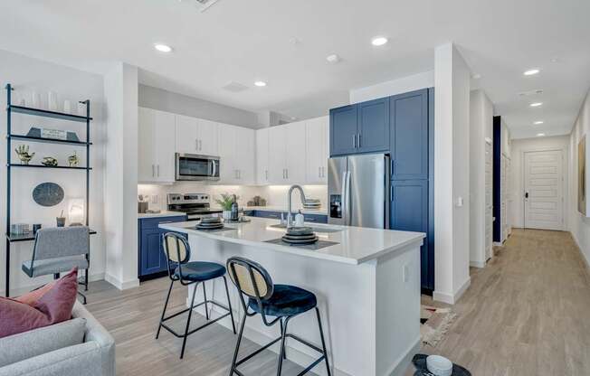 A kitchen with a white island and blue cabinets.