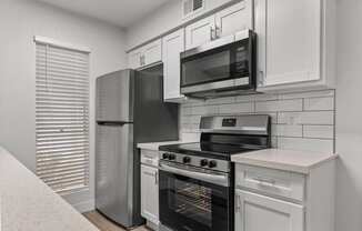 a kitchen with white cabinets and stainless steel appliances and a refrigerator