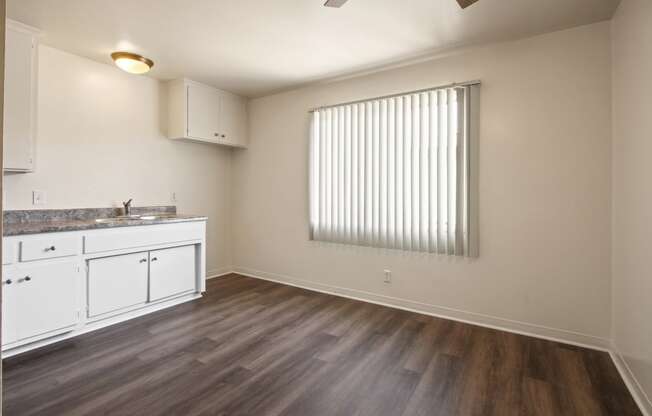 Dining area with ceiling fan, kitchen at the left, wood flooring throughout