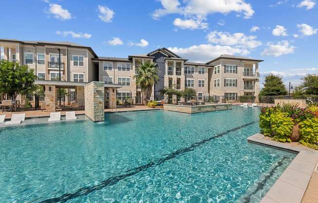 A large swimming pool in front of apartment buildings.