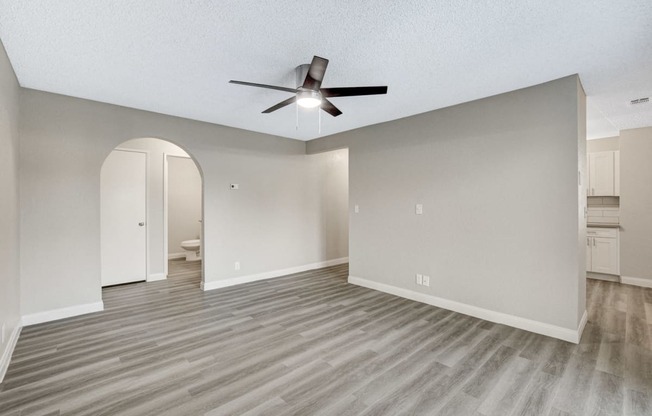 an empty living room with a ceiling fan