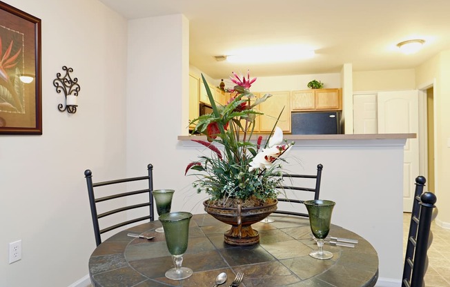 A dining table with a vase of flowers and two glasses on it.