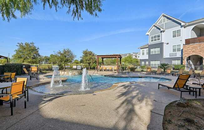A pool area with a waterfall and lounge chairs.