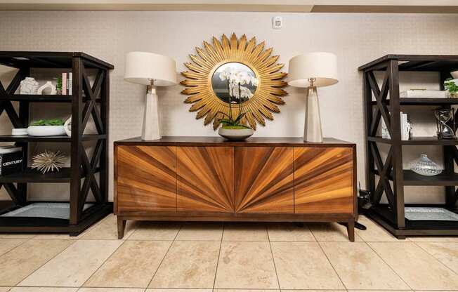 A wooden dresser with a sunburst mirror on top is flanked by two bookcases.