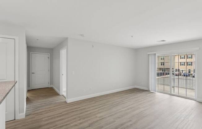 A spacious room with wooden flooring and white walls.