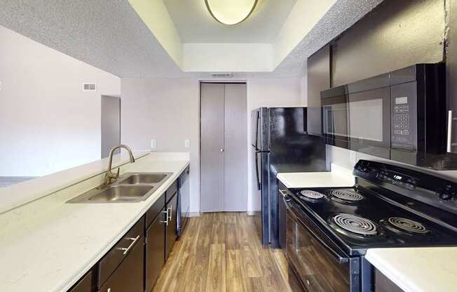 A kitchen with black appliances and white countertops.