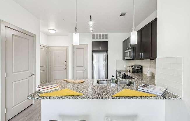 A kitchen with a granite countertop and dark cabinets at GreenVue Apartments in Richardson, TX