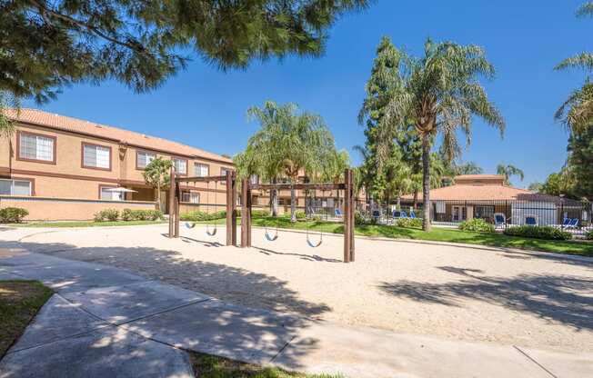 a playground in front of a school with trees and a building