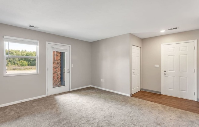 an empty living room with two doors and a window