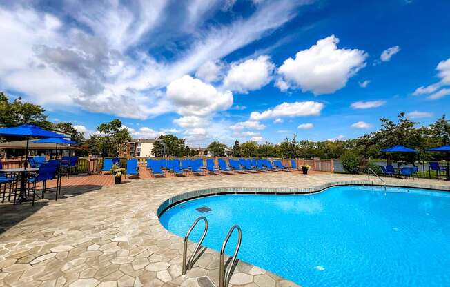 A swimming pool surrounded by blue lounge chairs and umbrellas.