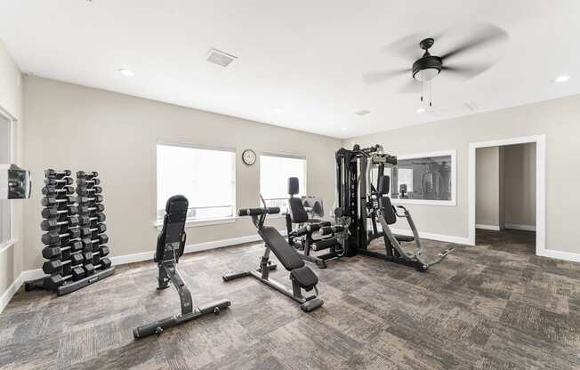 A spacious home gym with a variety of equipment including a weight rack, treadmill, and a bench press.