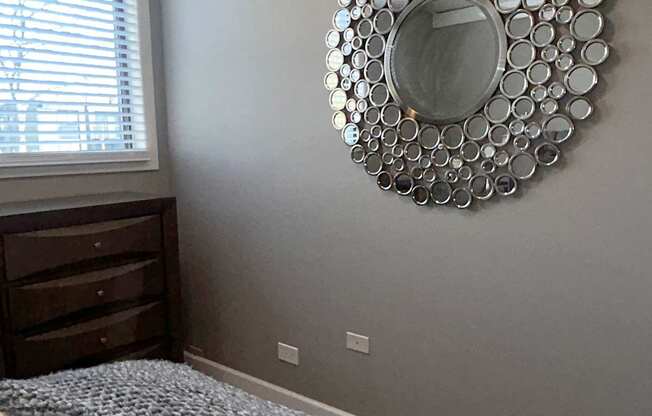 A bedroom with a bed, a dresser, and a mirror on the wall.