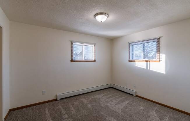 a bedroom with two windows. Fargo, ND North Manor Apartments