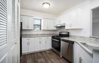 A kitchen with white cabinets and a stainless steel dishwasher and oven at Foxwood and The Hermitage in Portage, MI
