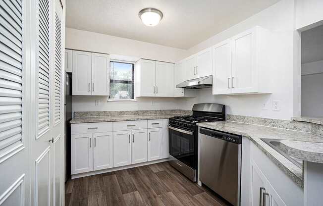 A kitchen with white cabinets and a stainless steel dishwasher and oven at Foxwood and The Hermitage in Portage, MI