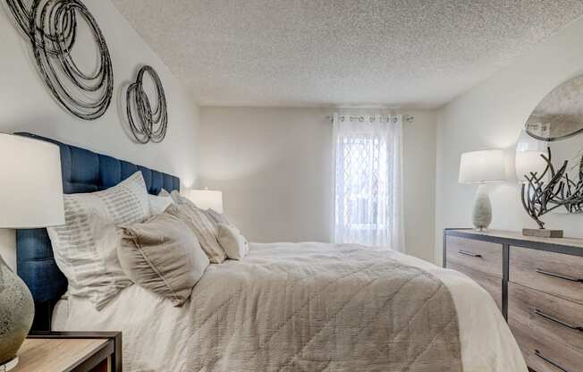 A bedroom with a bed, nightstand, and wall decor.