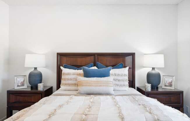 a bedroom with a bed with blue pillows and two lamps
