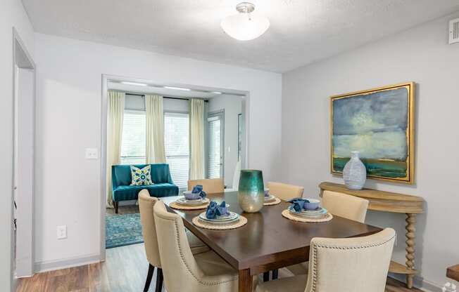 a dining room with a table and chairs and a living room with windows
