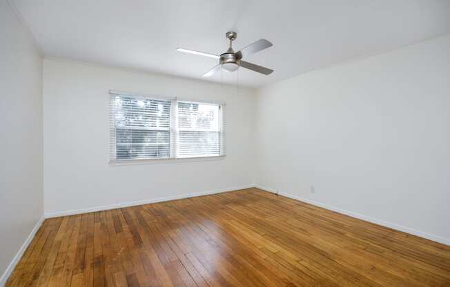 an empty living room with wood floors and a ceiling fan