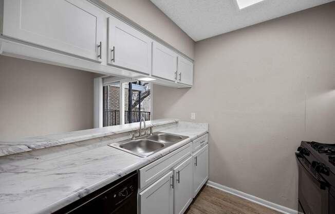 A kitchen with white cabinets and a marble countertop.