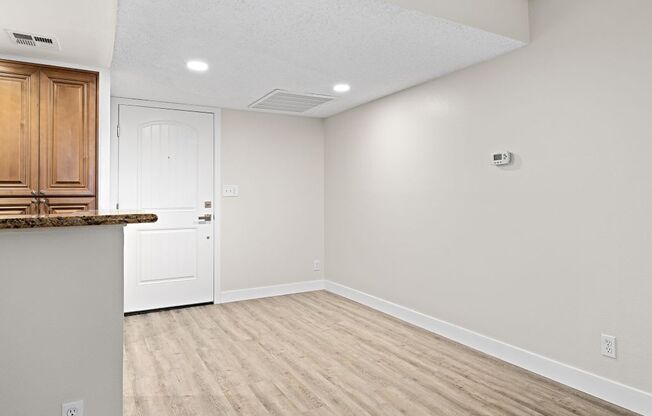 a kitchen and dining room with white walls and wood floors