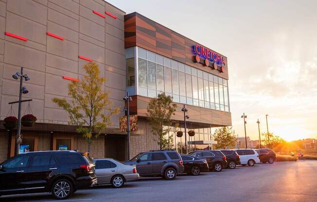 A Cineplex movie theater with cars parked in front.