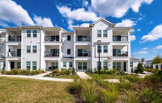 A white apartment building with balconies and a clear blue sky.