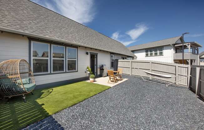 a backyard with a fence and a patio with chairs and grass